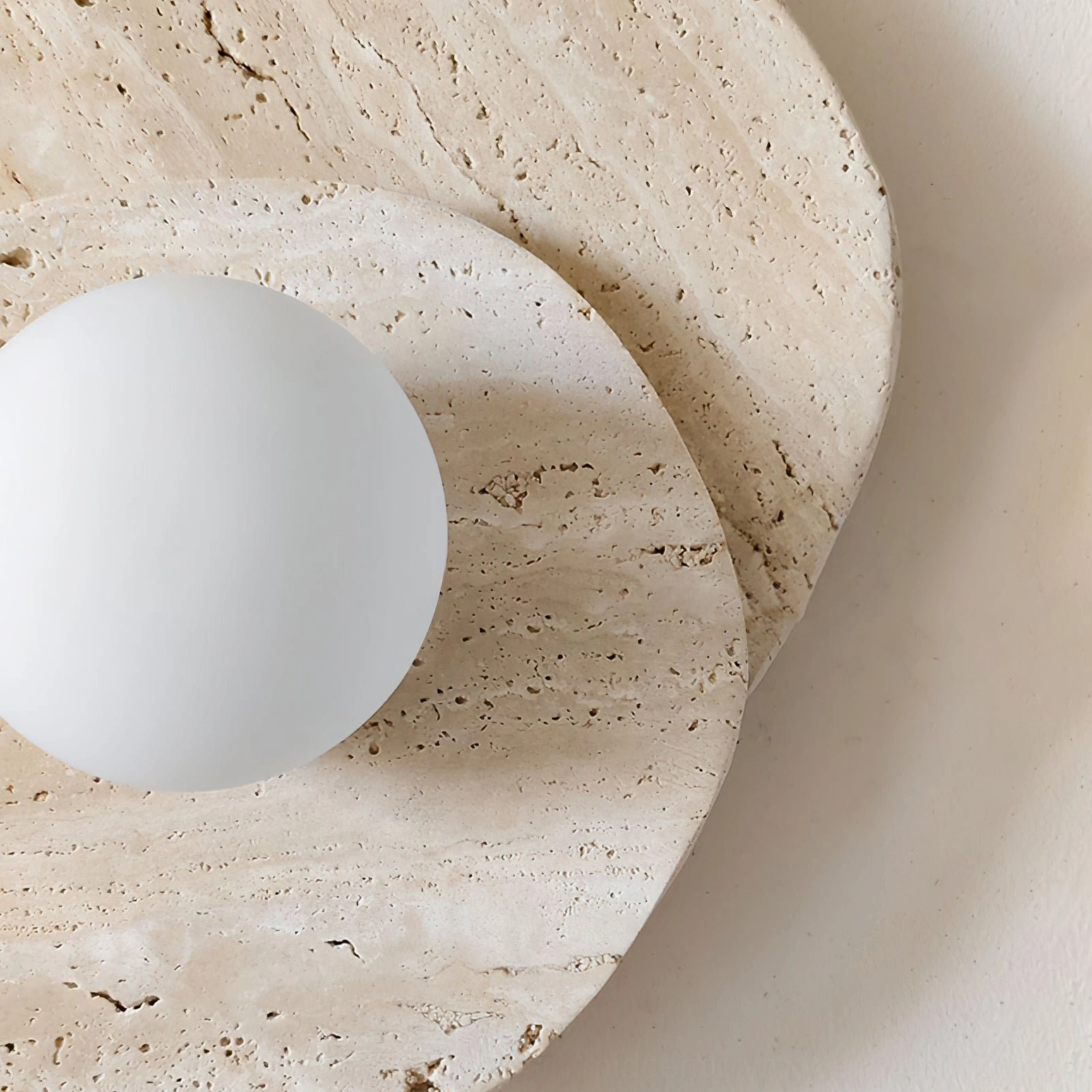 Ner minimalist travertine wall lamp front flat view against beige wall, minimalist wabi-sabi aesthetic