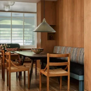 Nerissa pendant light hanging above dining booth, vintage brass finish, interior design scene with wooden booth seating