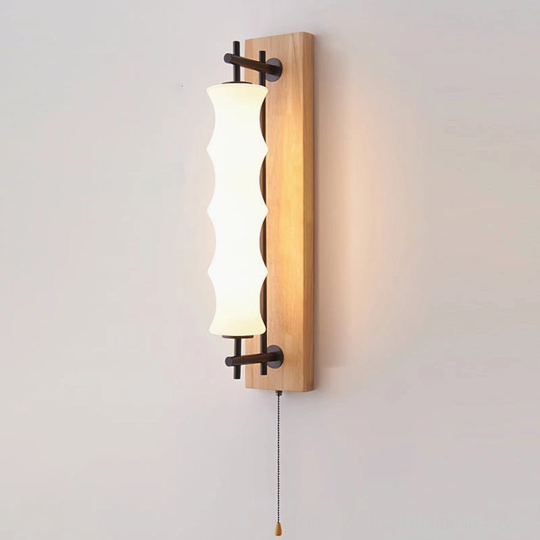 Nesta wall sconce with light wood finish on neutral wall, frontal view showing warm luminous glow