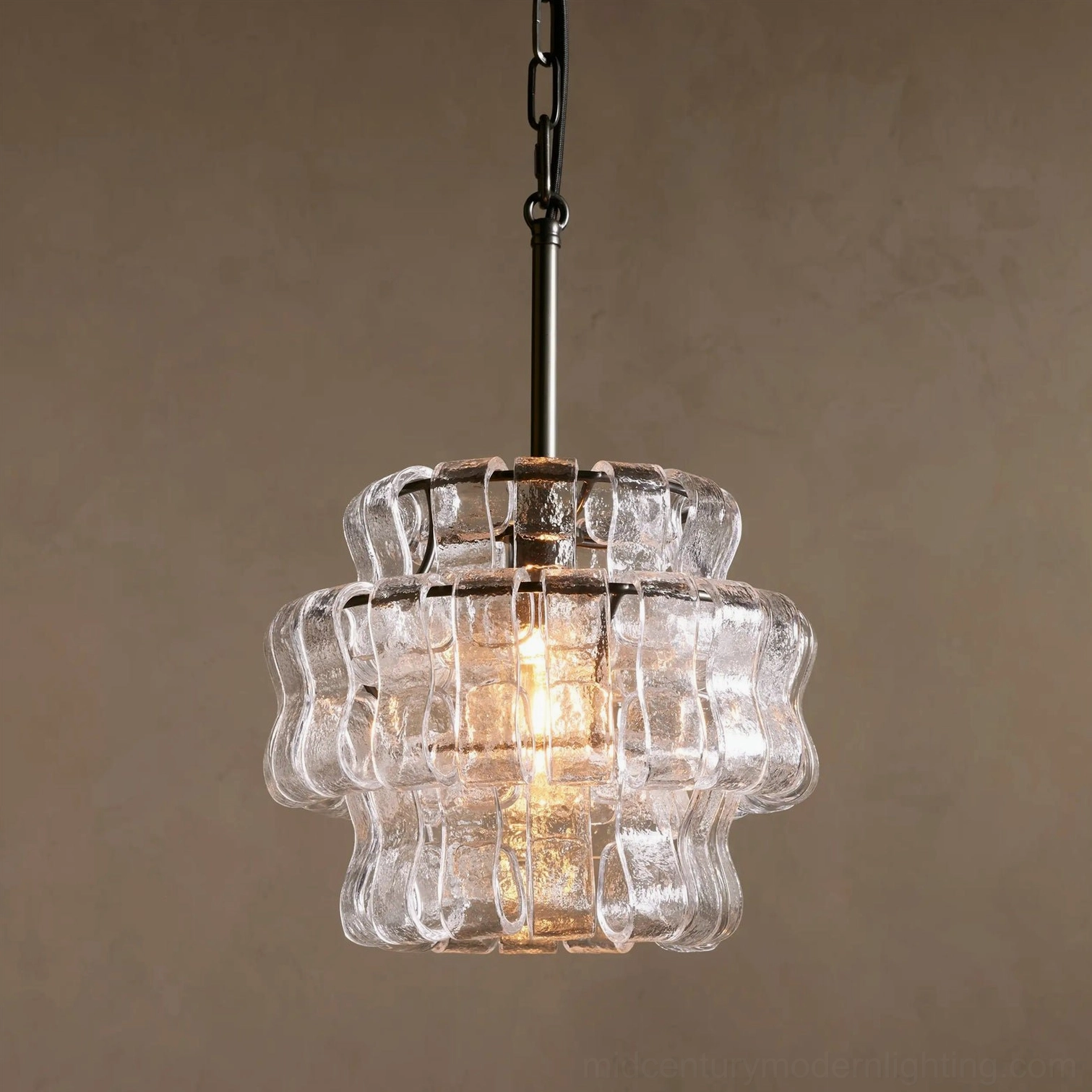 Illuminated Nirsa pendant light with soft golden glow through rippled glass, interior setting