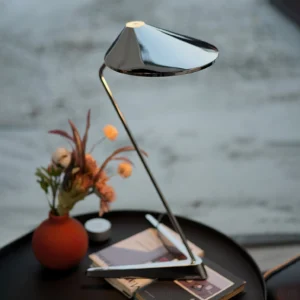 Modern chrome desk lamp with zigzag metal stem on coffee table interior scene