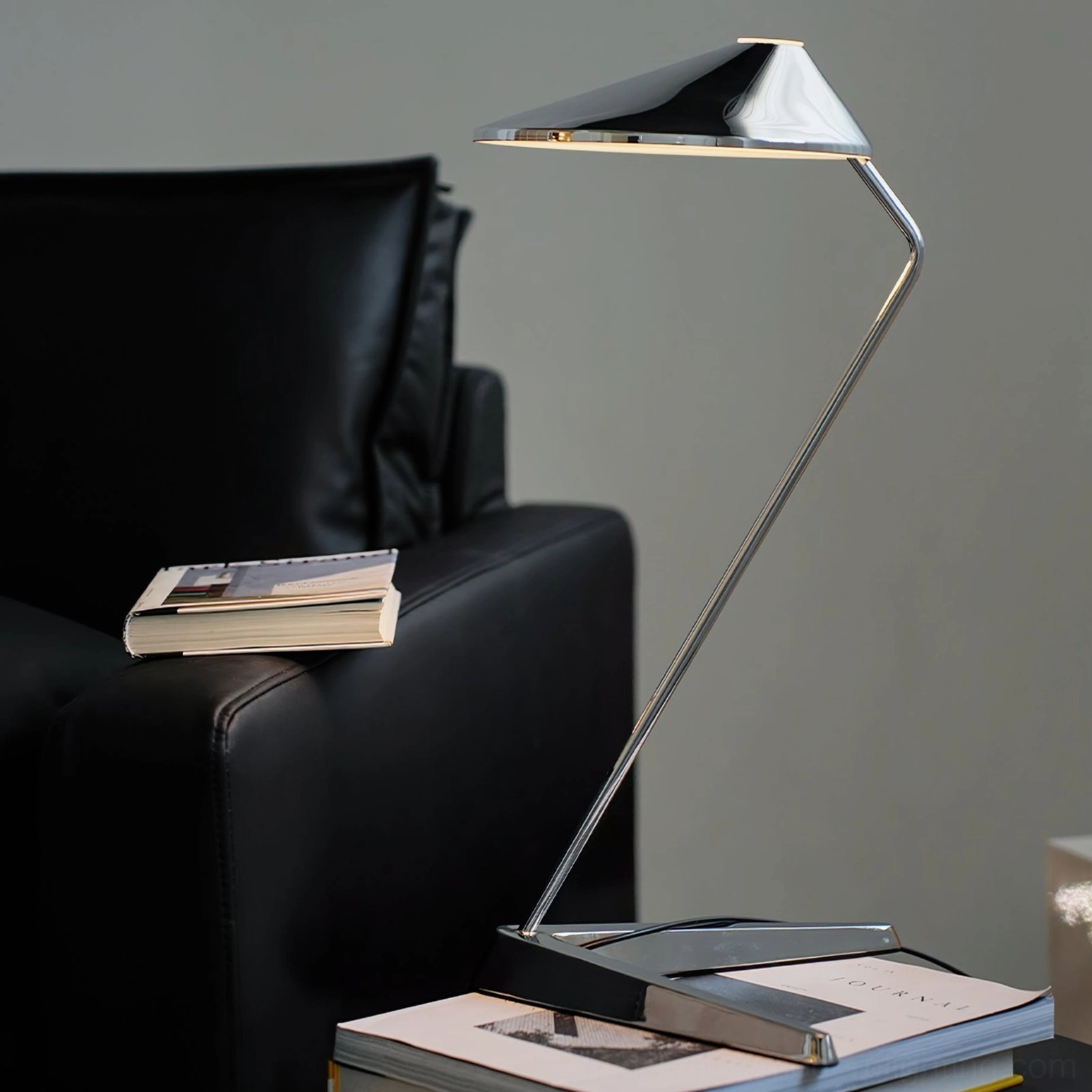 Modern task lamp on stacked books living room with black leather sofa