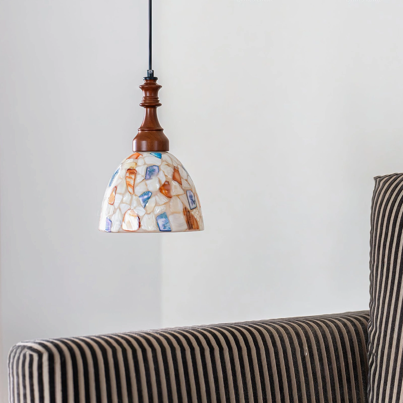 Nonna pendant light frontal hanging view in living room beside striped sofa, understated vintage home decor aesthetic