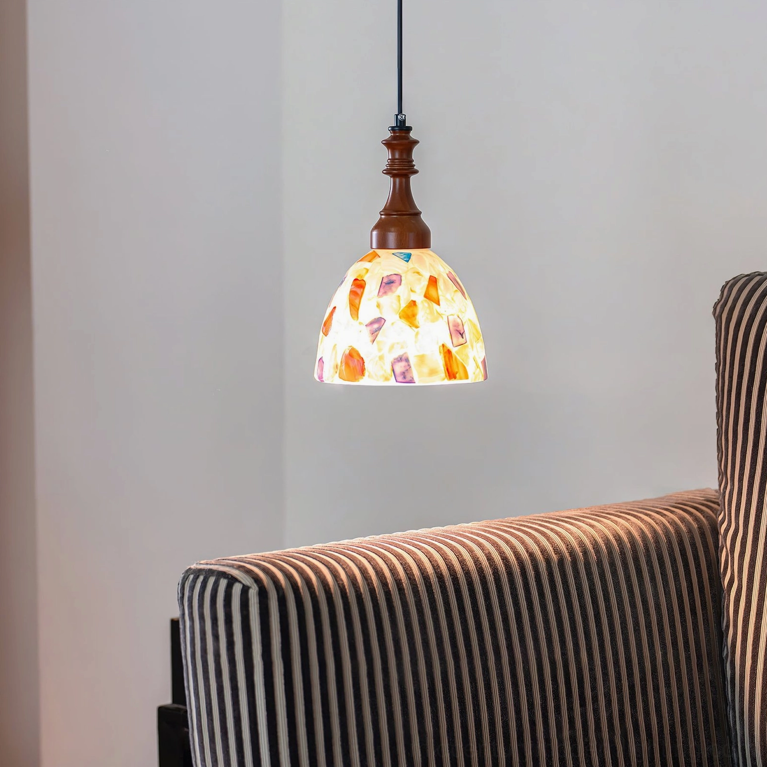 Nonna mosaic pendant light side close-up beside round white table in cozy living room setting