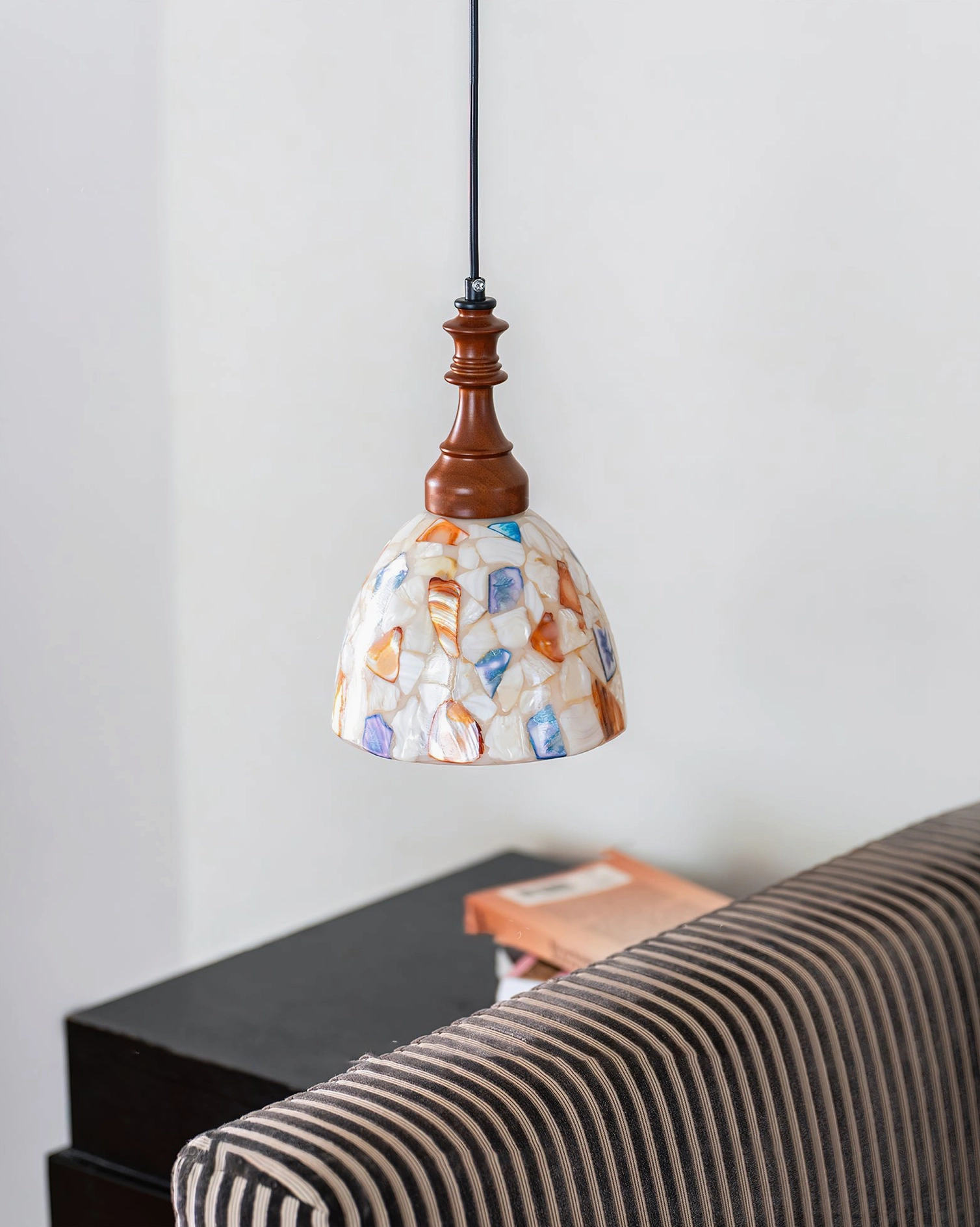 Nonna pendant light flat frontal view in living room beside striped sofa, simple vintage decorative lighting fixture