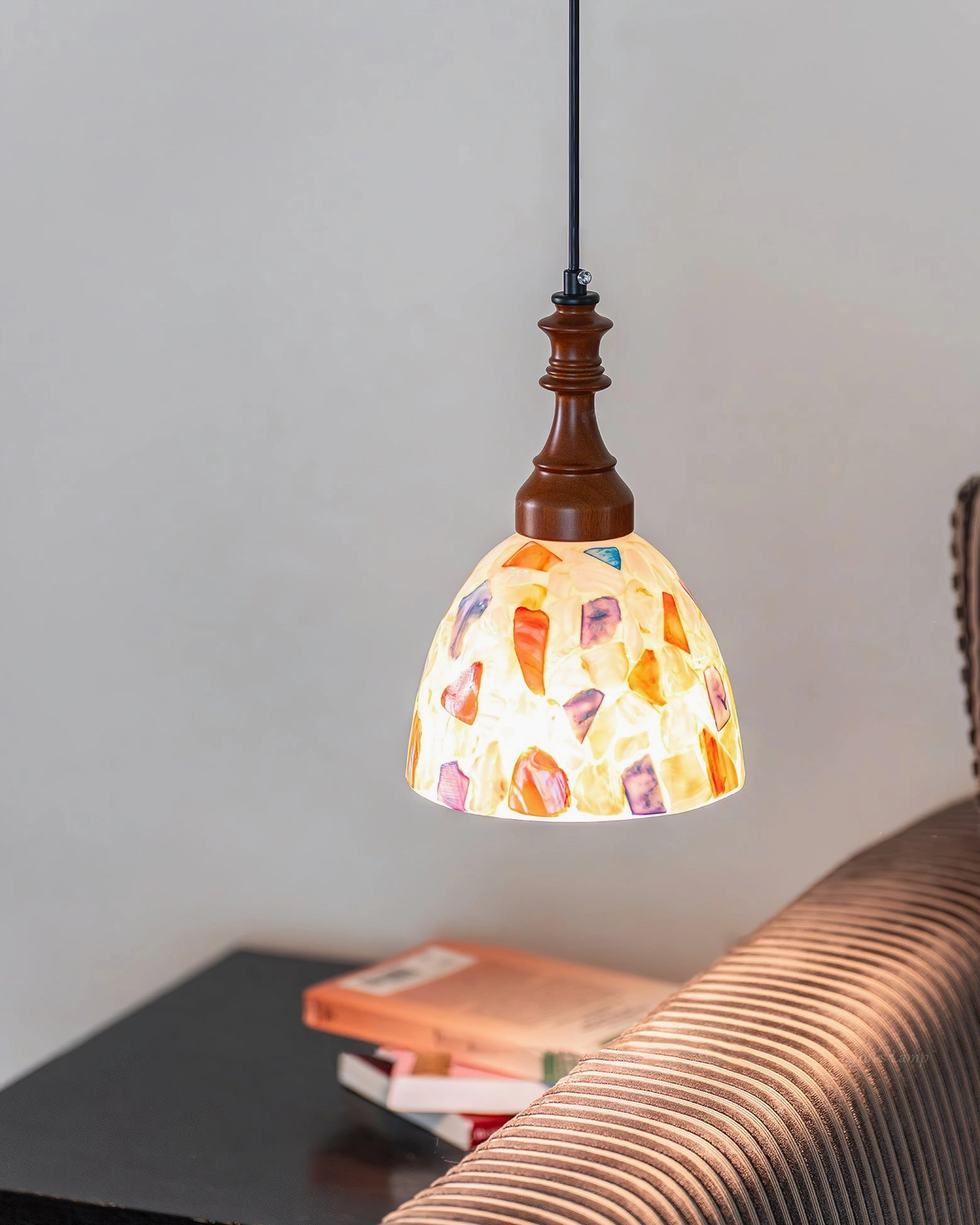Nonna vintage pendant light minimalist setting with side table and stacked books, warm mosaic glass illumination