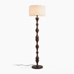 Norden carved wood floor lamp with walnut finish and beige fabric shade, frontal studio view
