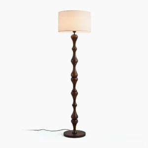 Norden carved wood floor lamp with walnut finish and beige fabric shade, frontal studio view