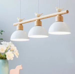 Three-head bird chandelier in home dining setting with warm glowing lampshades and light wood finish, home interior display