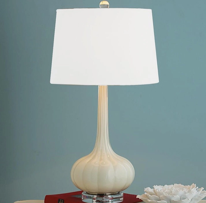 Cream white ceramic glass table lamp with opaque gourd base on accent table against teal wall