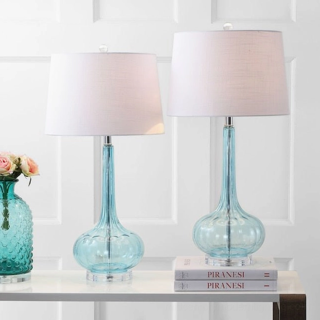 Pair of blue ceramic glass table lamps with matching fabric shades on white indoor side table