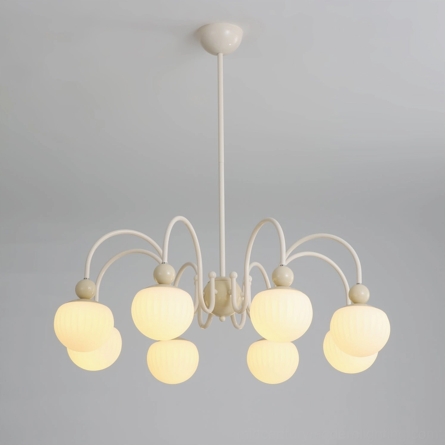 Lit Notti mid-century chandelier illuminated overhead view showing warm glowing frosted glass shades and cream metal frame