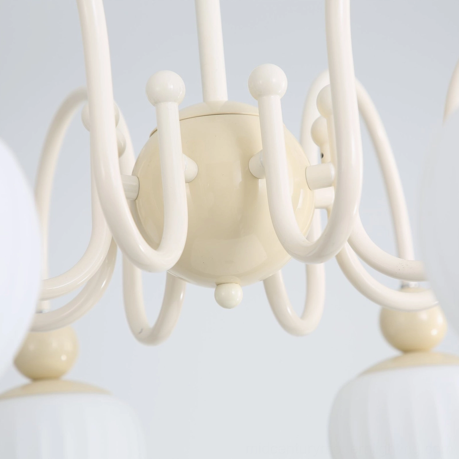 Close-up detail of Notti chandelier curved cream metal arm with spherical decorative knob and glass shade connection
