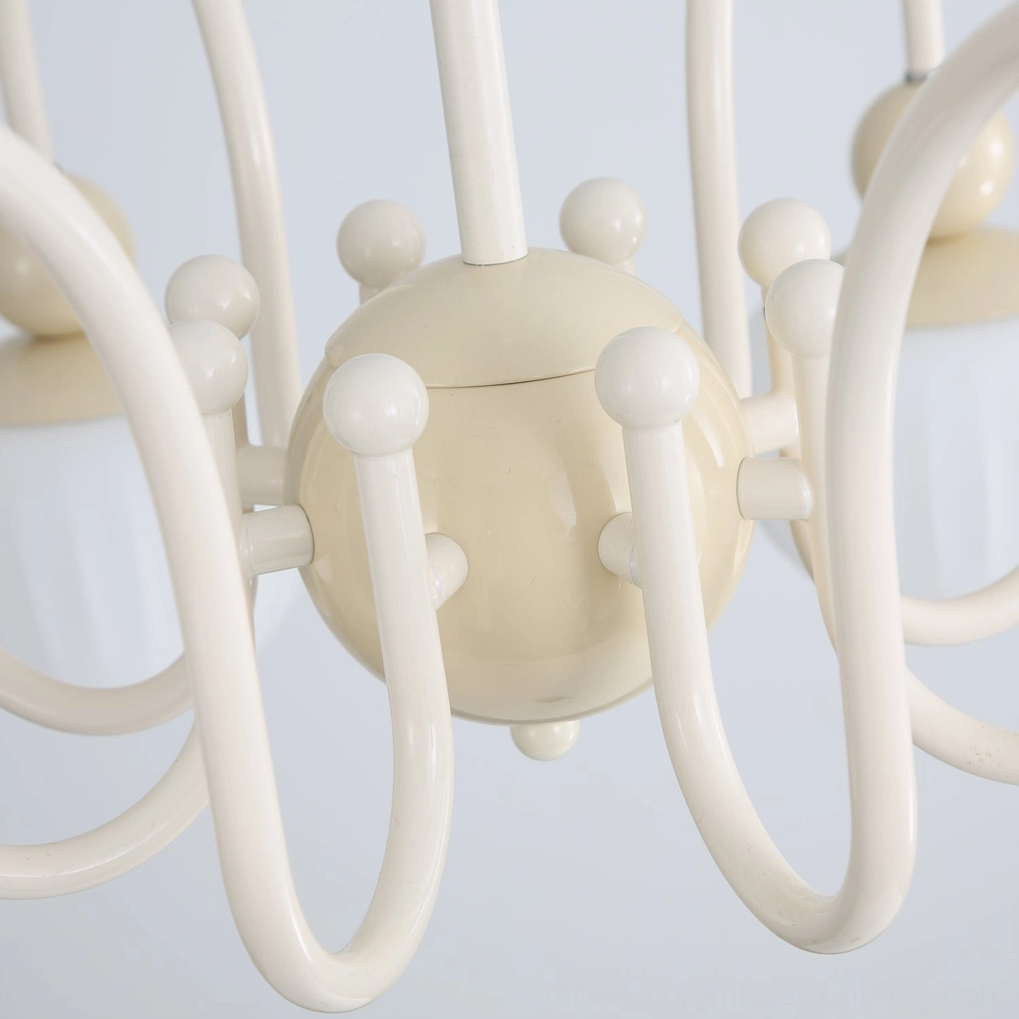 Close-up frontal detail of Notti chandelier matte cream metal arms with round decorative knobs and glass connections