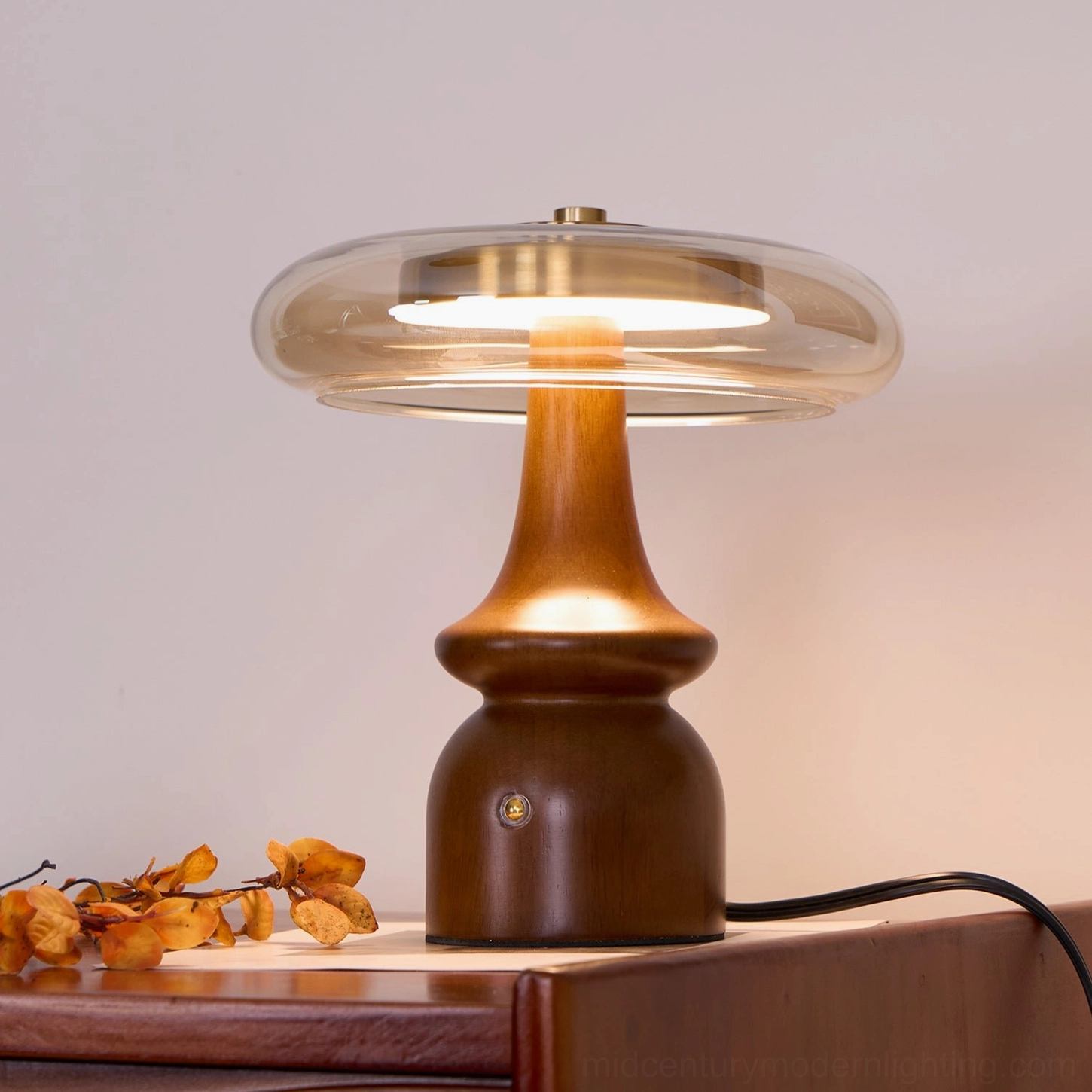 Nova table lamp direct front close-up view illuminated on wooden side table with warm glowing light and focused illumination
