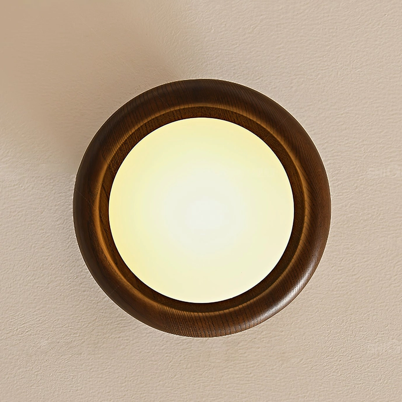 Novi mid-century ceiling fixture illuminated with warm amber light and dark walnut wood ring