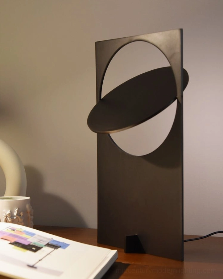 OBJ 01 table lamp side profile view, matte black metal construction, crescent cutout shadow design, minimalist proportions