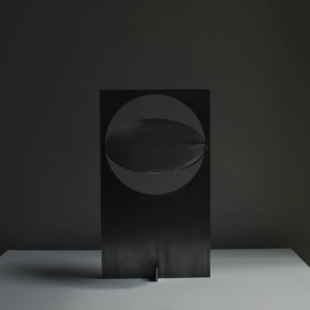 OBJ 01 geometric table lamp unlit front view showcasing matte black metal body and circular disc shade design, minimalist studio background