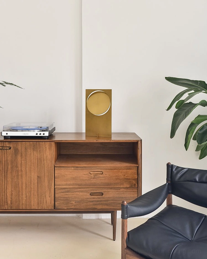 OBJ 01 brass gold minimalist table lamp in modern living room, placed on wooden storage cabinet with leather armchair background, room lighting context