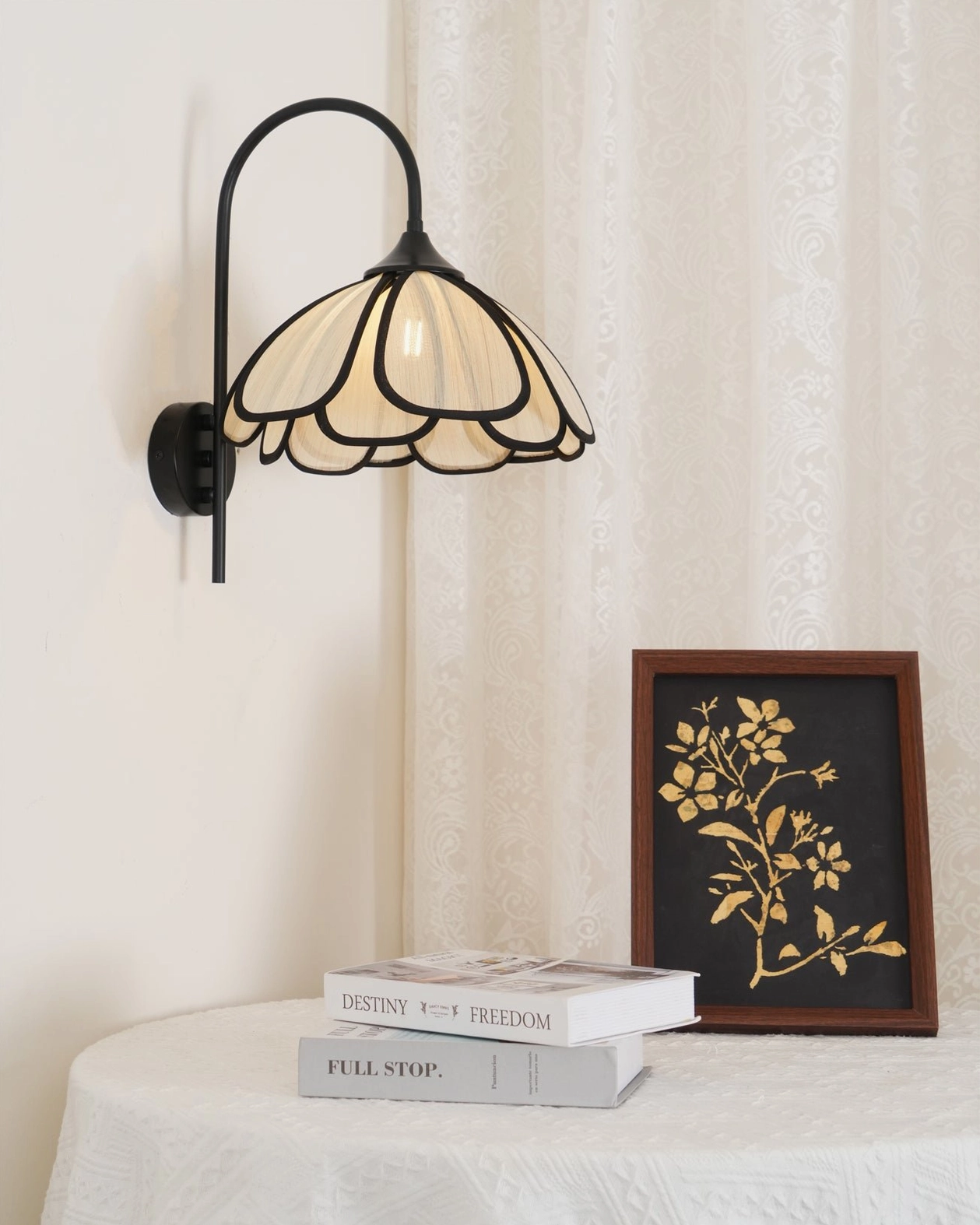 Okai wall lamp styled in bedroom setting with side table decor and stacked books