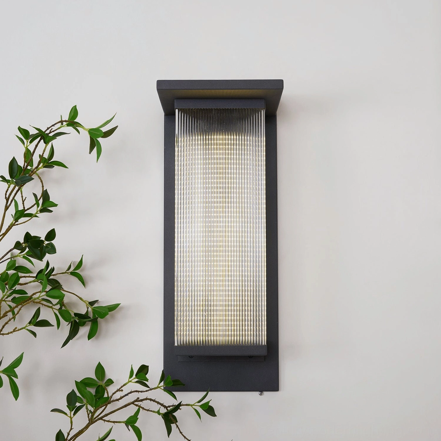 Oleron Box outdoor wall lamp front lit view, warm 3000K LED light, ribbed acrylic diffuser glowing, matte black frame, contemporary architecture