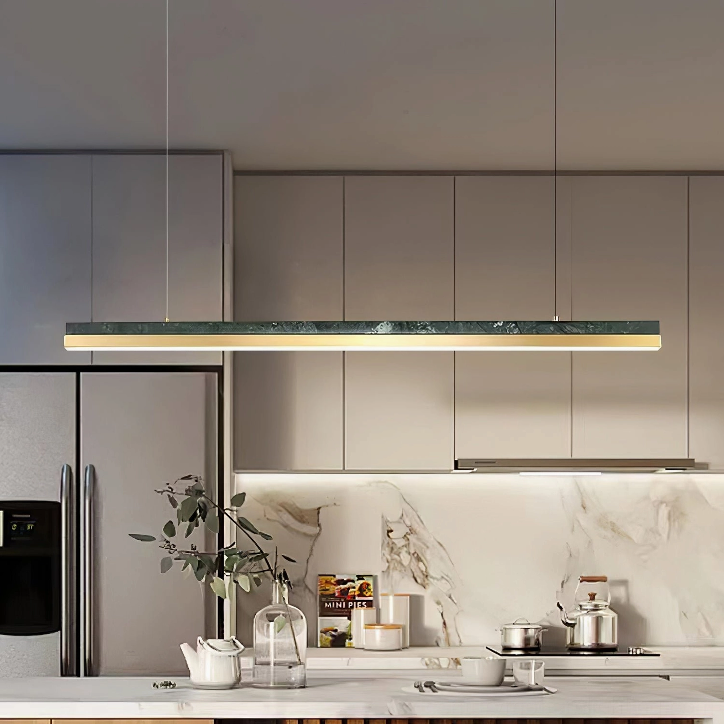 One Word pendant light above light grey modern kitchen with marble countertop and natural plant styling