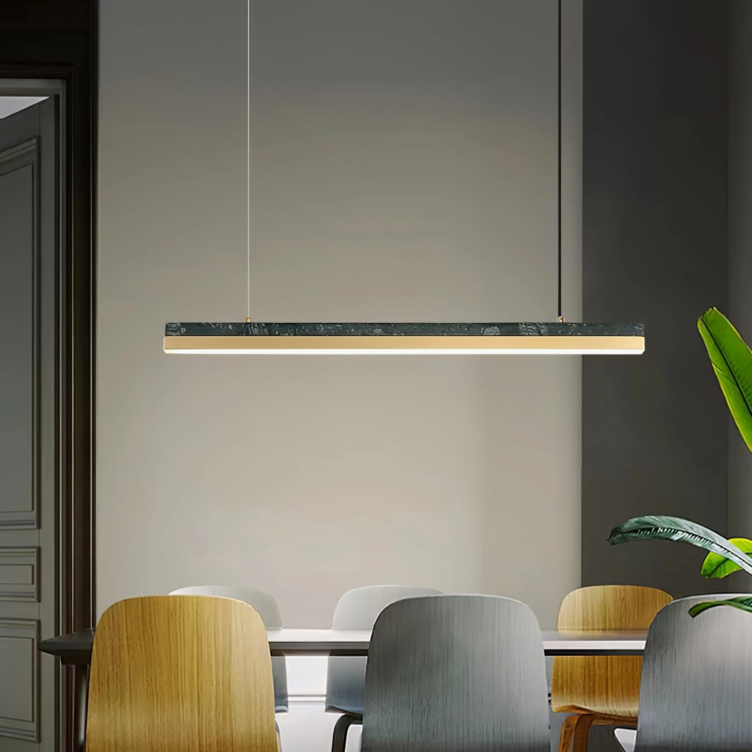 One Word linear pendant light above dining table in contemporary dining room setting with green plant styling