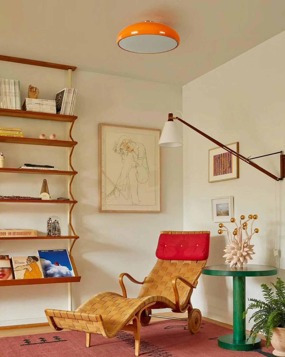 Orange semi-flush ceiling fixture mounted in vintage lounge space with warm retro interior design and silver metal base details
