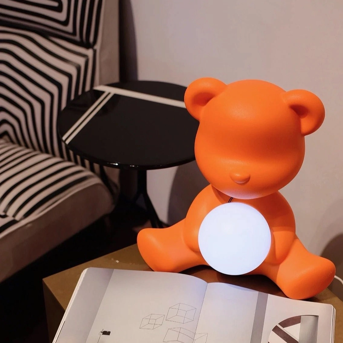 Orange teddy bear table lamp in modern living room beside striped sofa and round side table