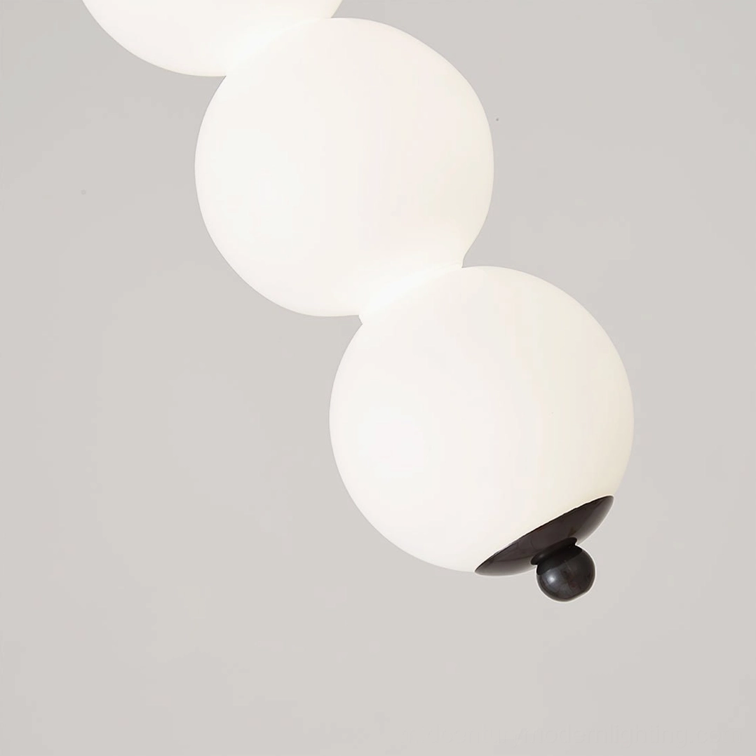 Orbet pendant lamp featuring stacked milk glass spheres and brass metal hardware detail