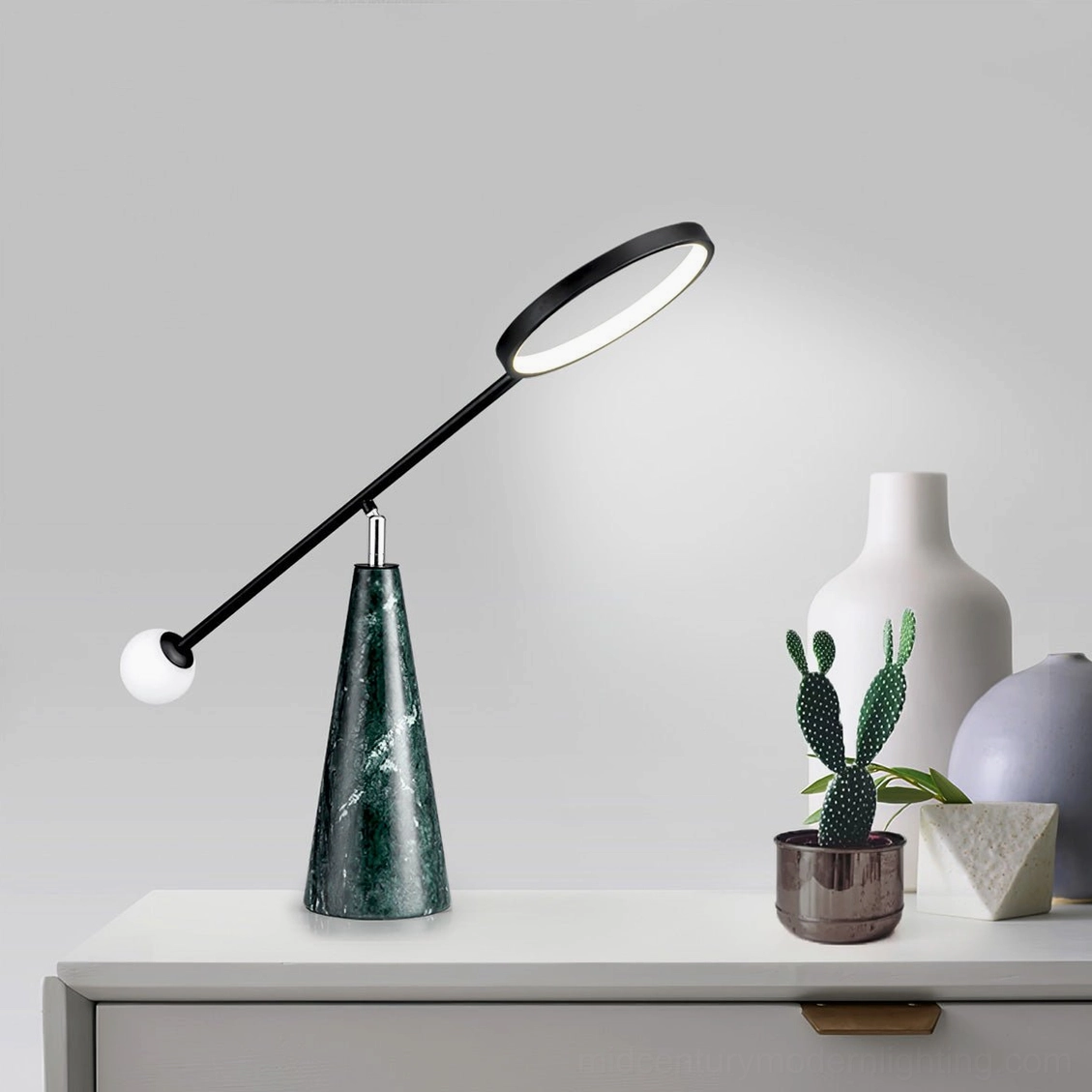 Orbit green marble lamp on white dresser with potted cactus and decorative vases, low angle view