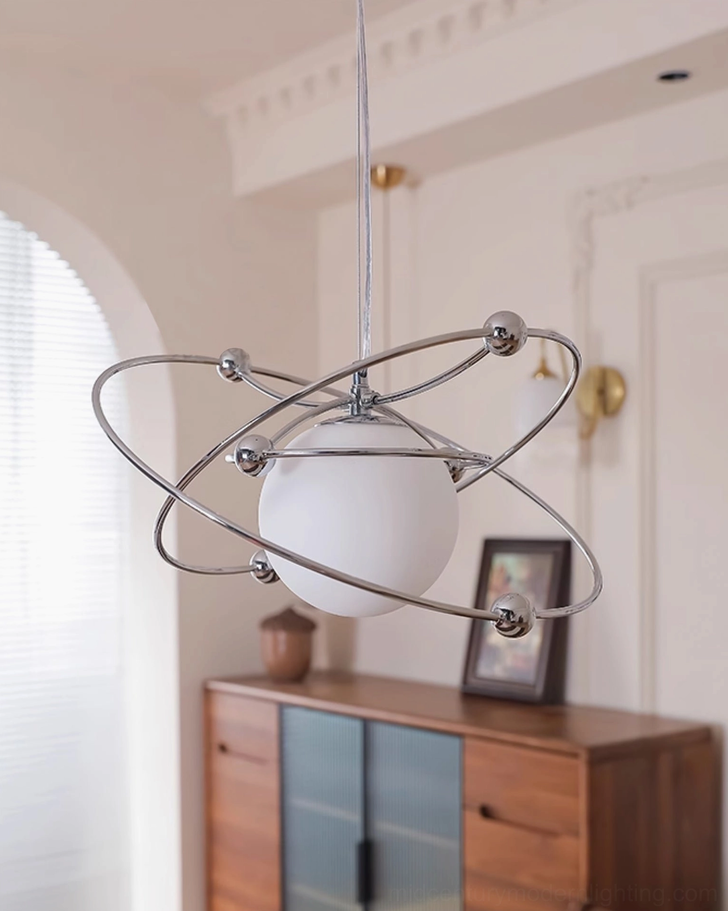 Space-age orbital pendant with frosted white shade in eclectic dining room with wall art