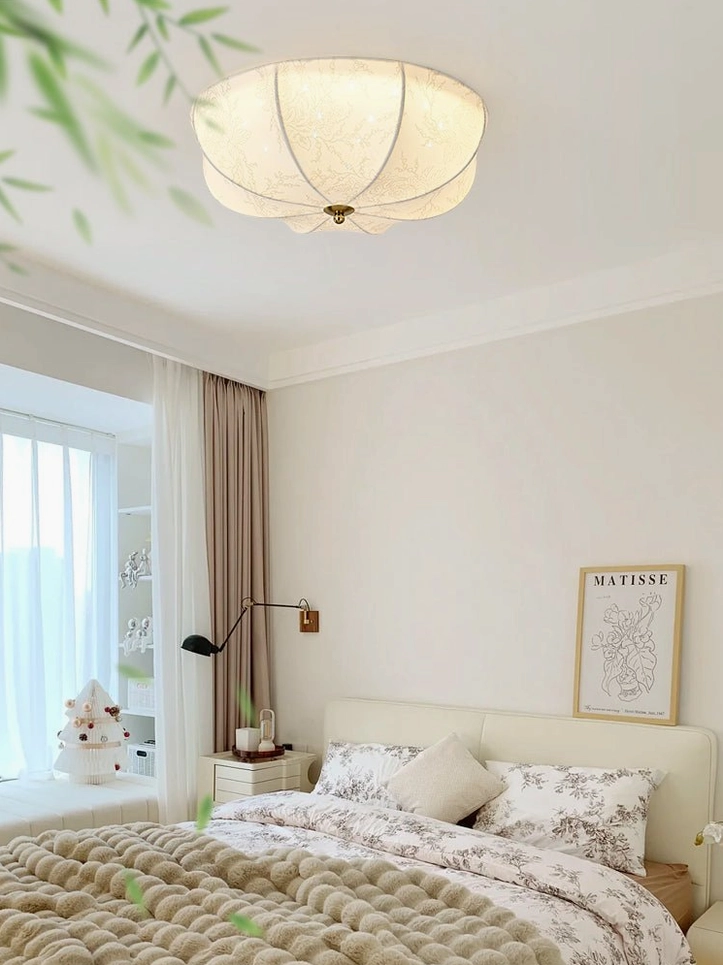Minimalist cozy bedroom with orchid fabric ceiling light providing soft warm illumination over bed in neutral interior
