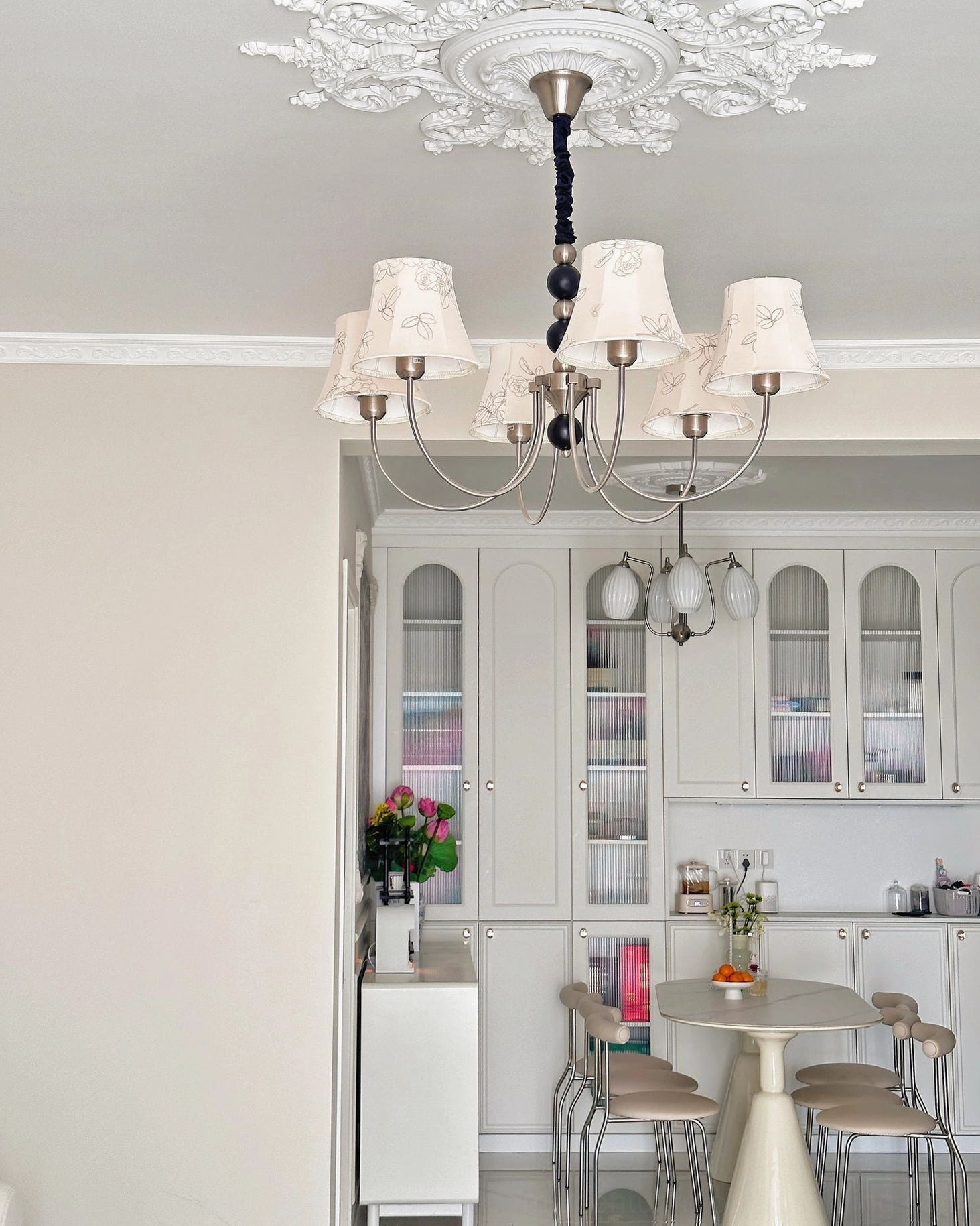 Eight-head fabric chandelier with silver frame in elegant dining room with ornate ceiling medallion