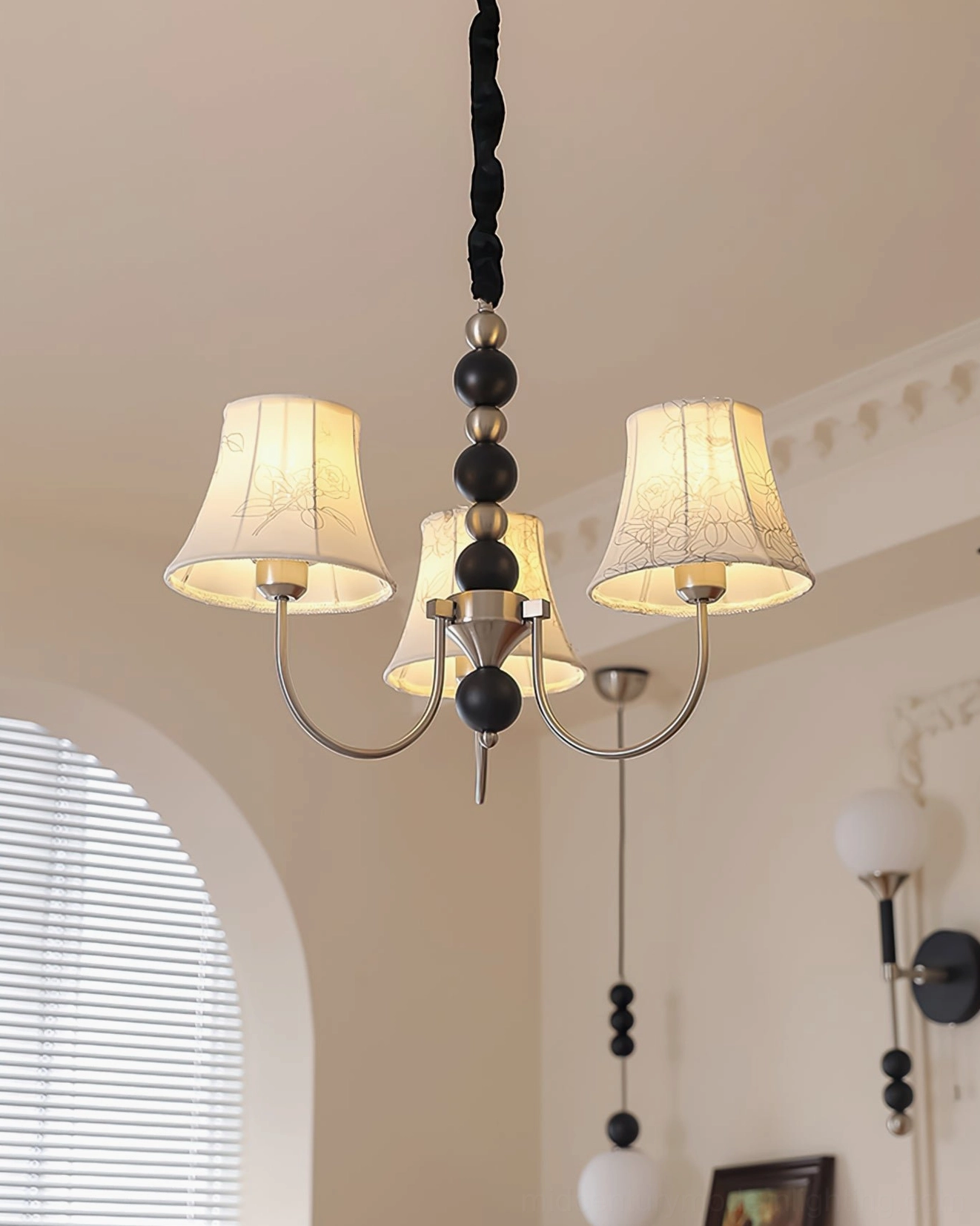 Multi-head fabric pendant light with dark metal accents in minimalist home interior, close-up overhead view