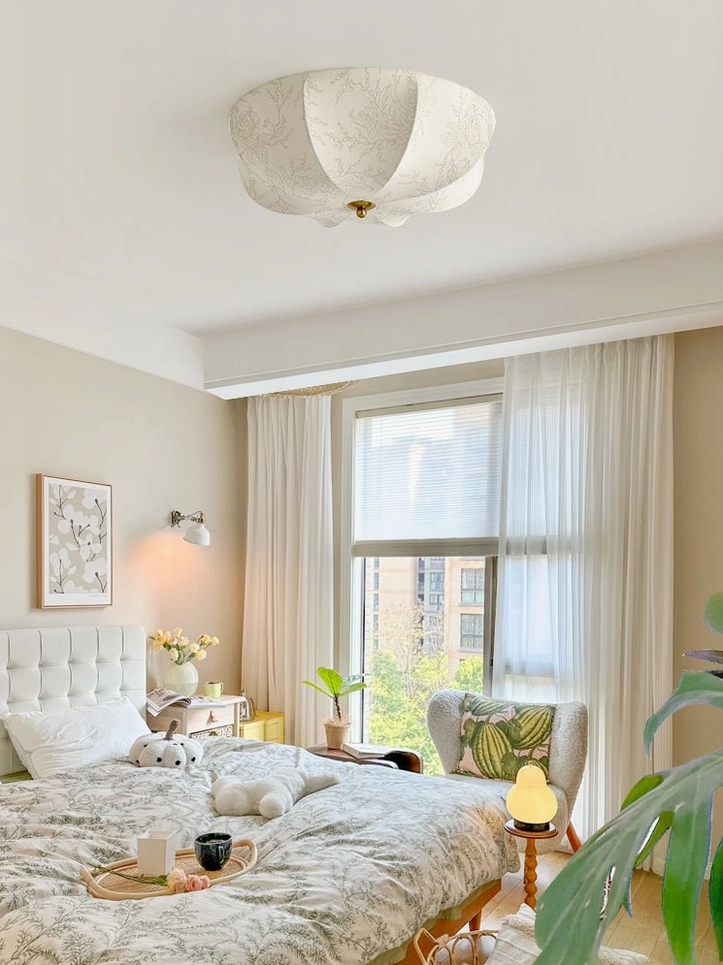 Wide bedroom view featuring orchid ceiling light creating French pastoral ambiance with natural window light and cozy furnishings