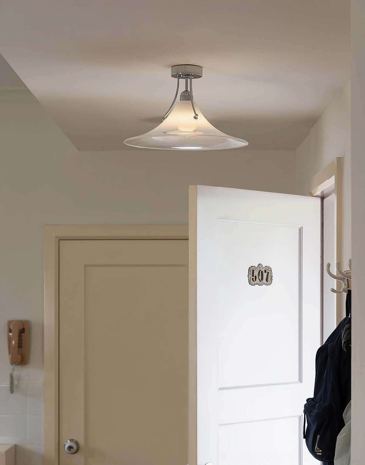 Semi-flush ceiling lamp in residential hallway with vintage wall phone showing sleek chrome hardware and compact design
