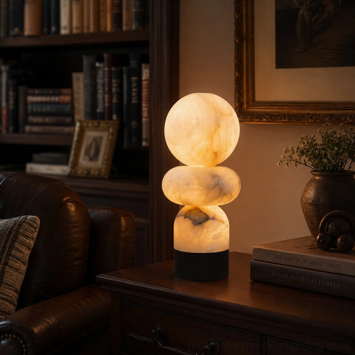 Orso alabaster lamp on dark wood study desk beside stacked books side angle view