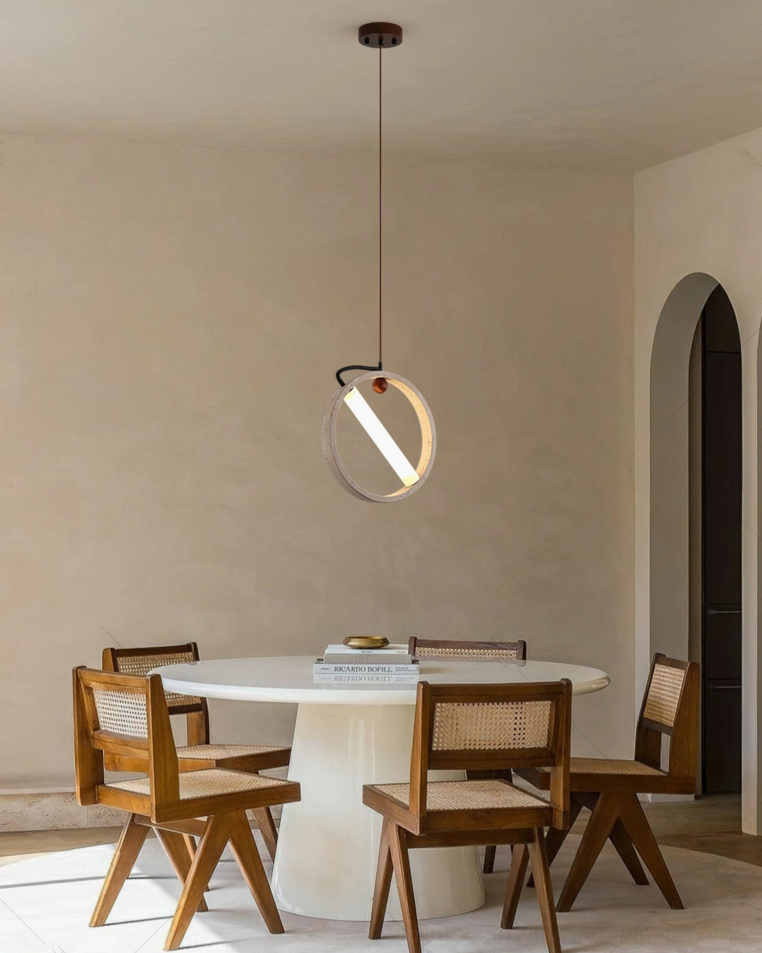 Orvion round pendant light in beige travertine creating intimate lighting in warm toned dining room