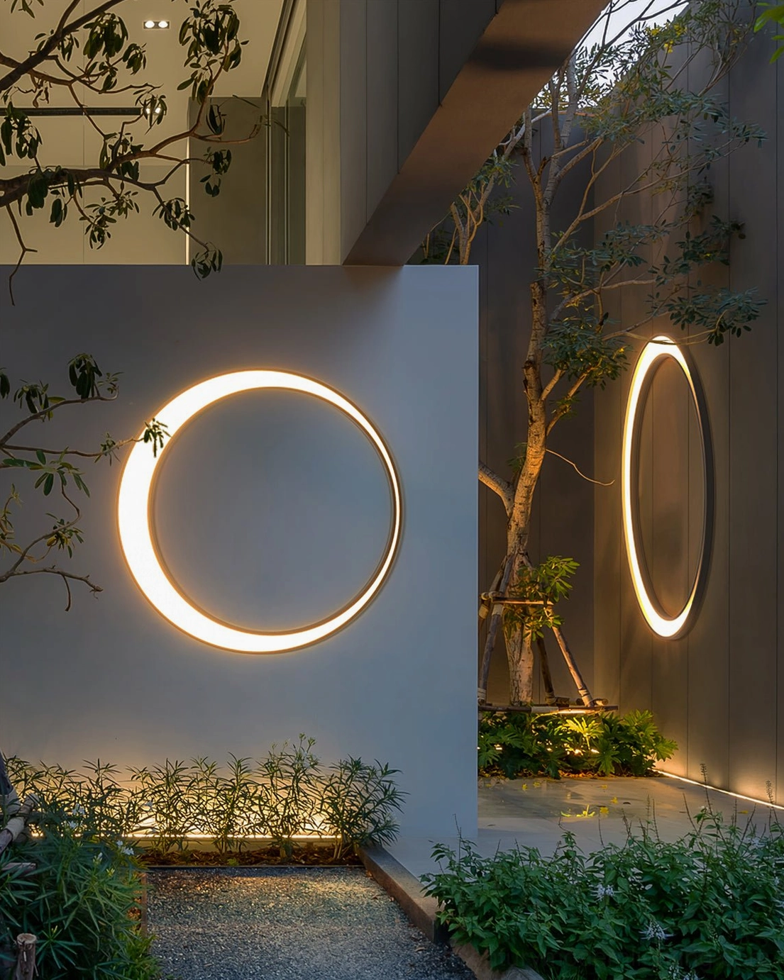 Circular LED outdoor wall lamps on separate exterior walls in narrow garden corridor demonstrating flexible installation options