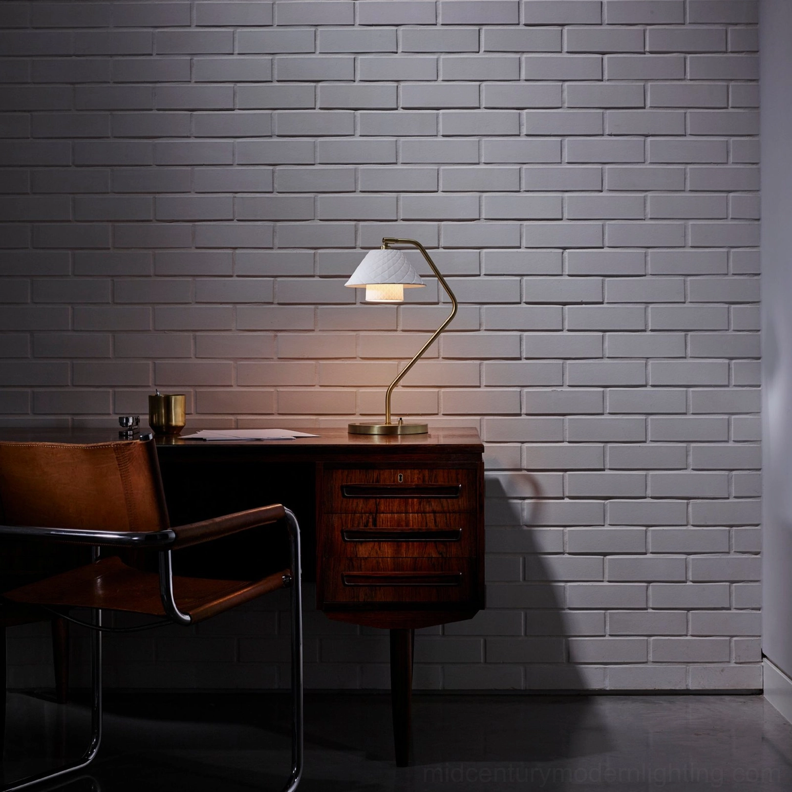 Oxford mid-century modern table lamp on dark wood desk with brick wall background, home office setting