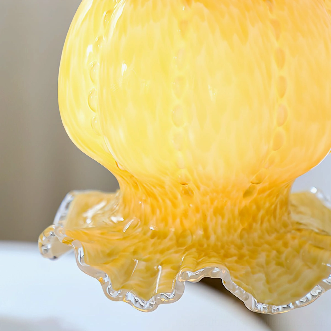 Ultra close-up of Ozera pendant light base showing detailed brass hardware and textured amber glass scalloped edge