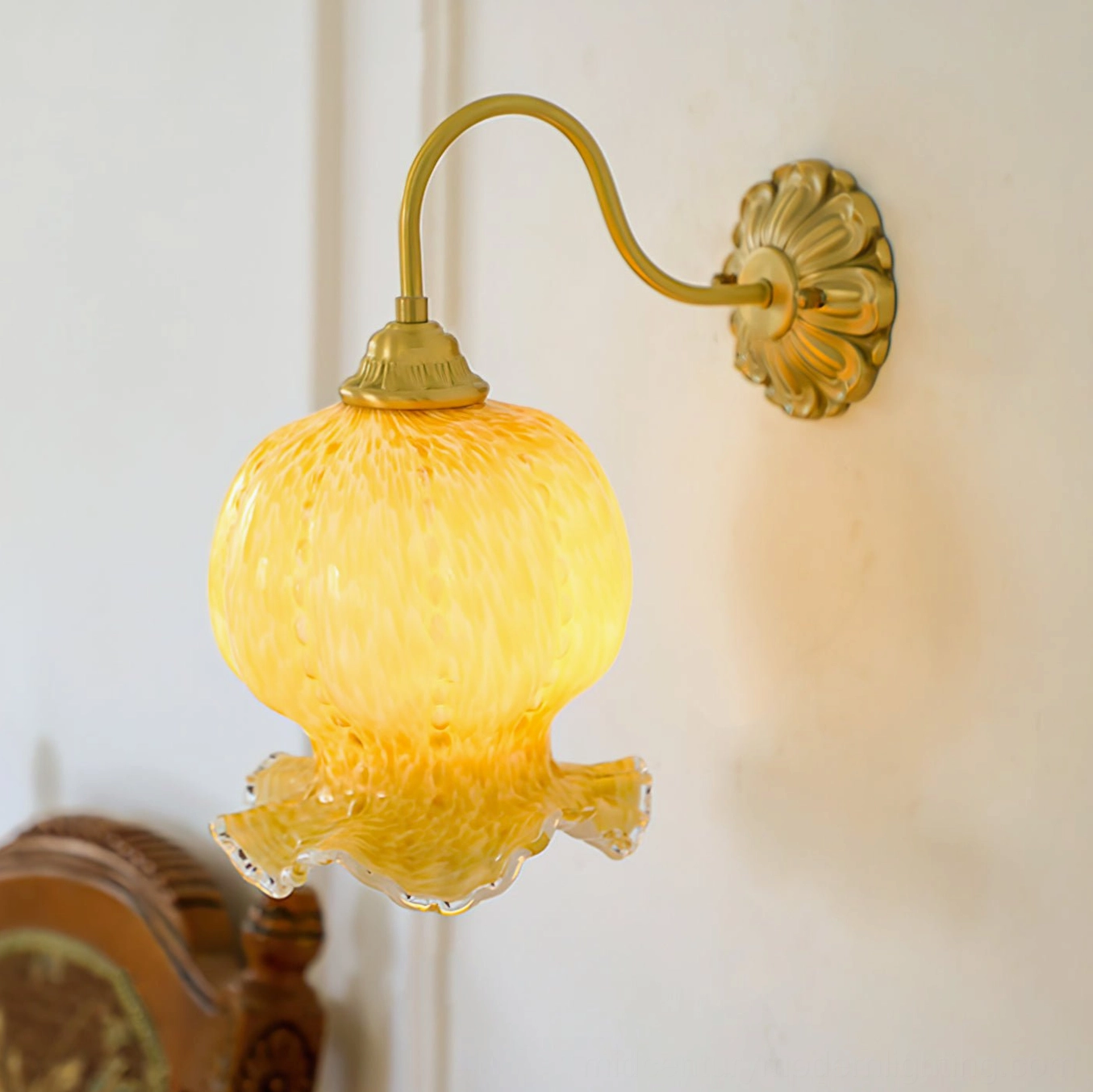 Ozera wall sconce lit with warm yellow glow showing marbled amber glass texture