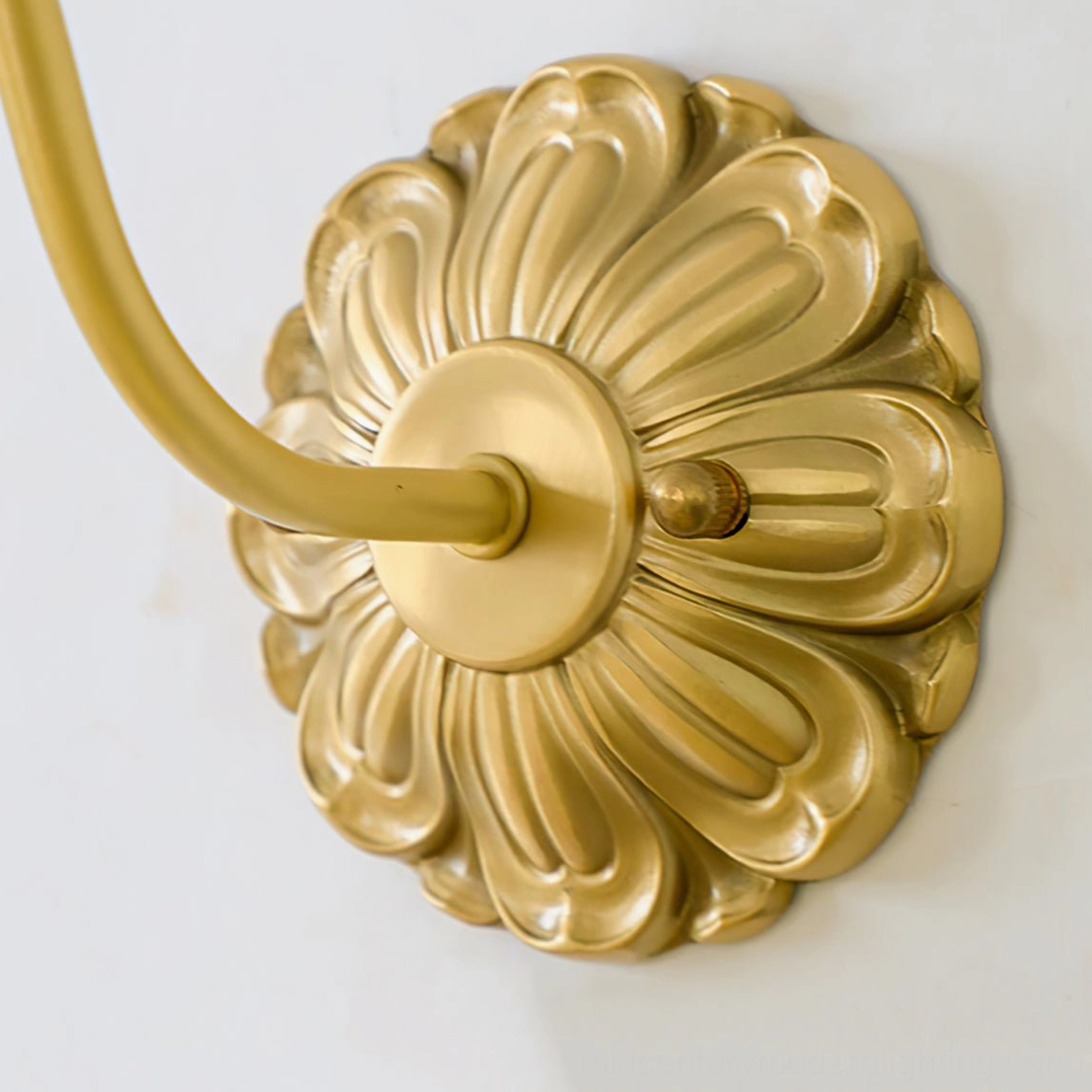 Ozera wall sconce close-up of petal-shaped embossed brass hardware and curved lamp arm
