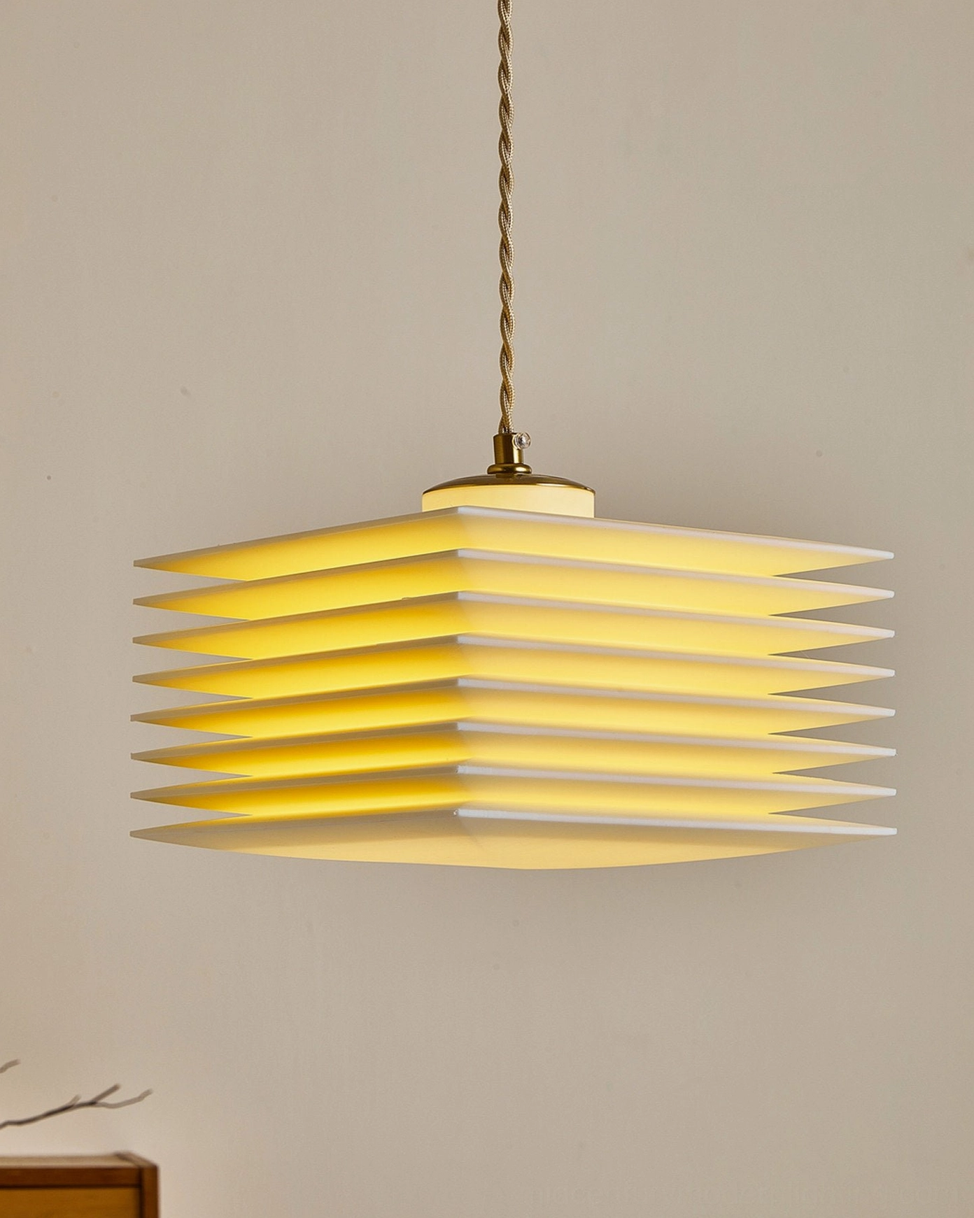 Illuminated pagoda pendant lamp casting layered light effects with twisted gold cord suspension