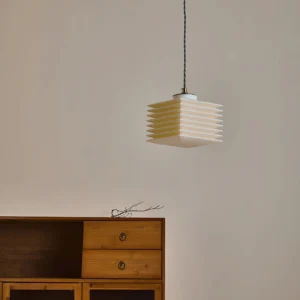 Mid-century modern pagoda pendant light glowing warm in Nordic minimalist room with wooden cabinet