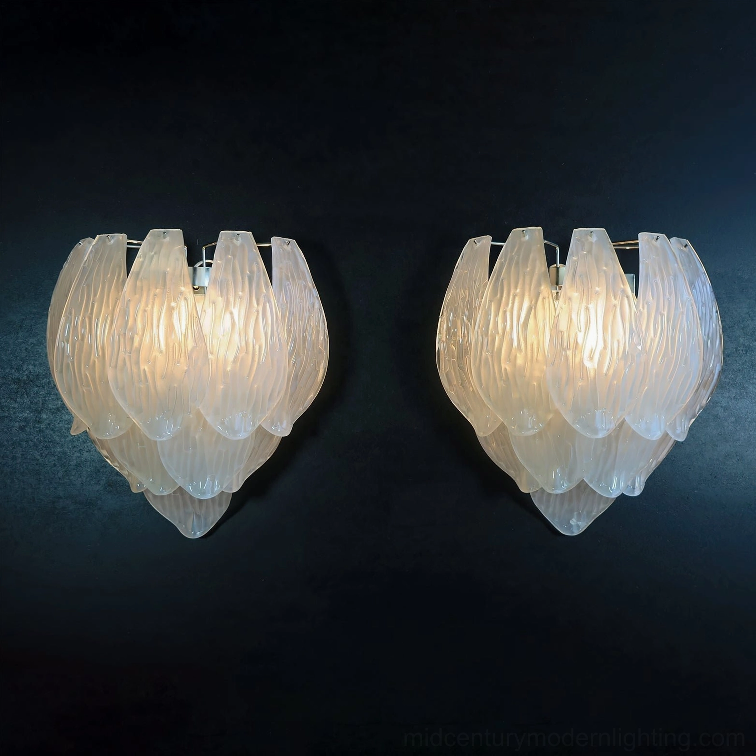 Two frosted petal wall sconces lit with warm ambient light on dark blue backdrop, romantic petal-shaped design