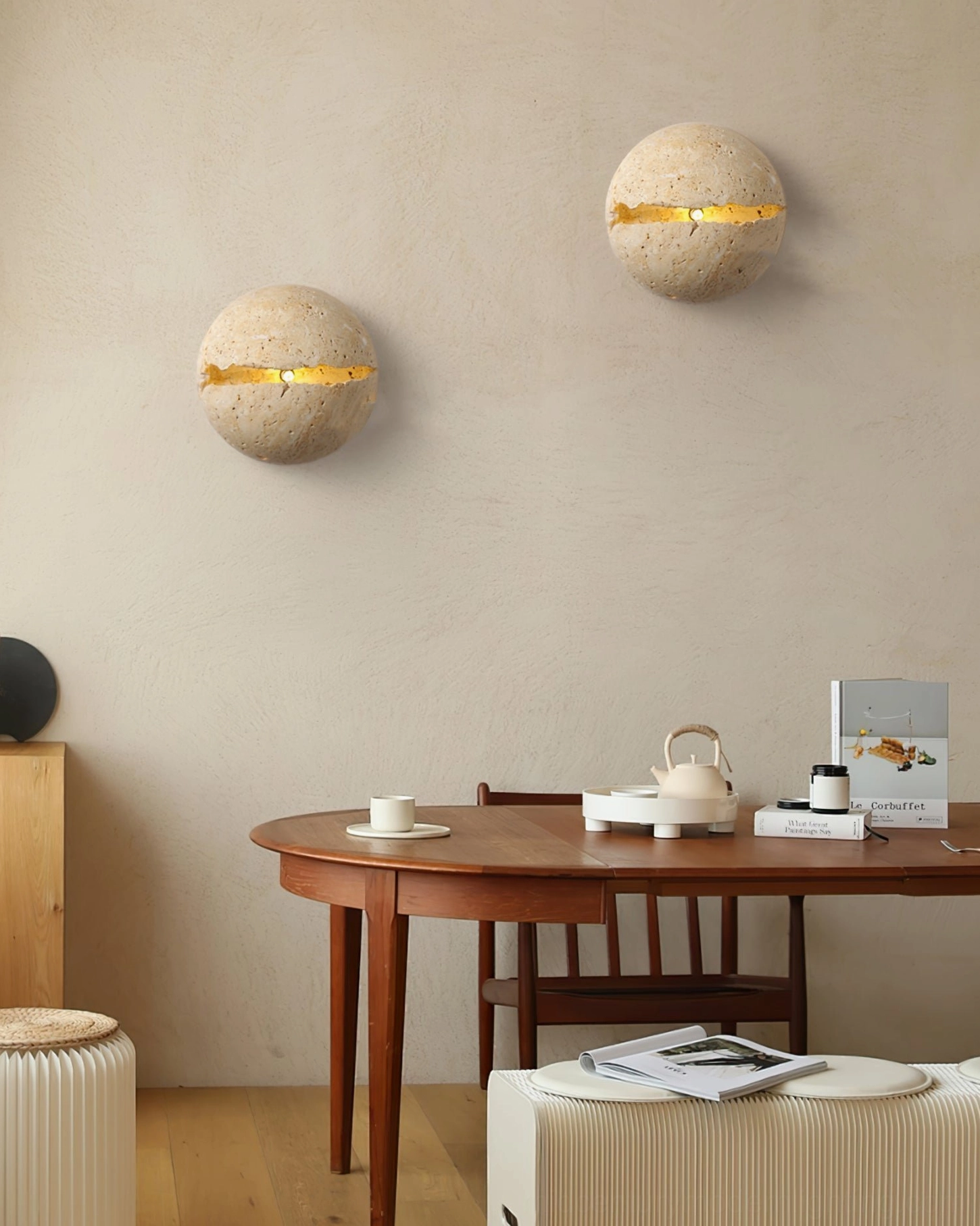 Two matching round travertine wall sconces as symmetrical pair in warm wooden dining room with minimalist decor