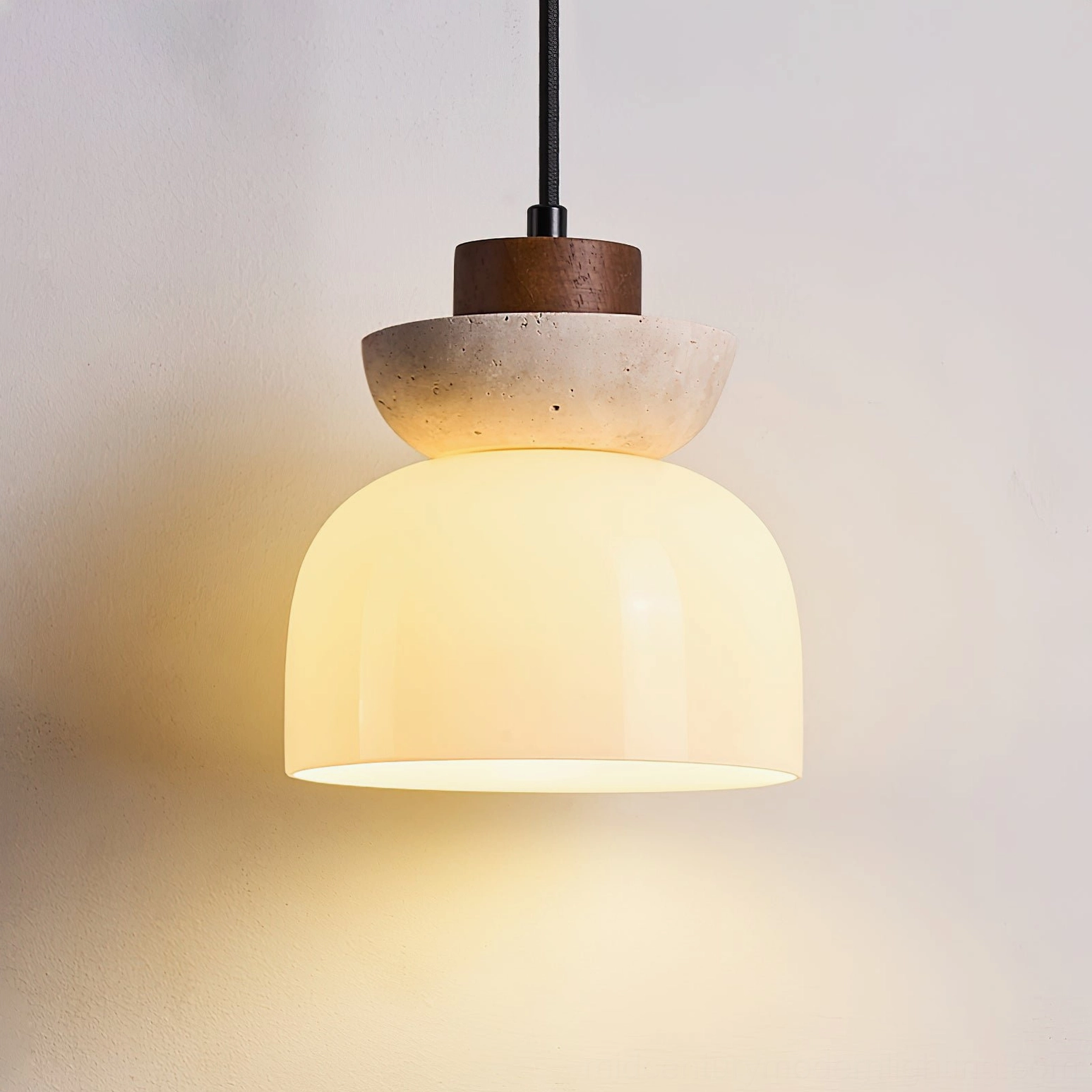 Lit Palak pendant lamp showing warm LED glow through opal white glass shade with travertine and wood top detail close-up