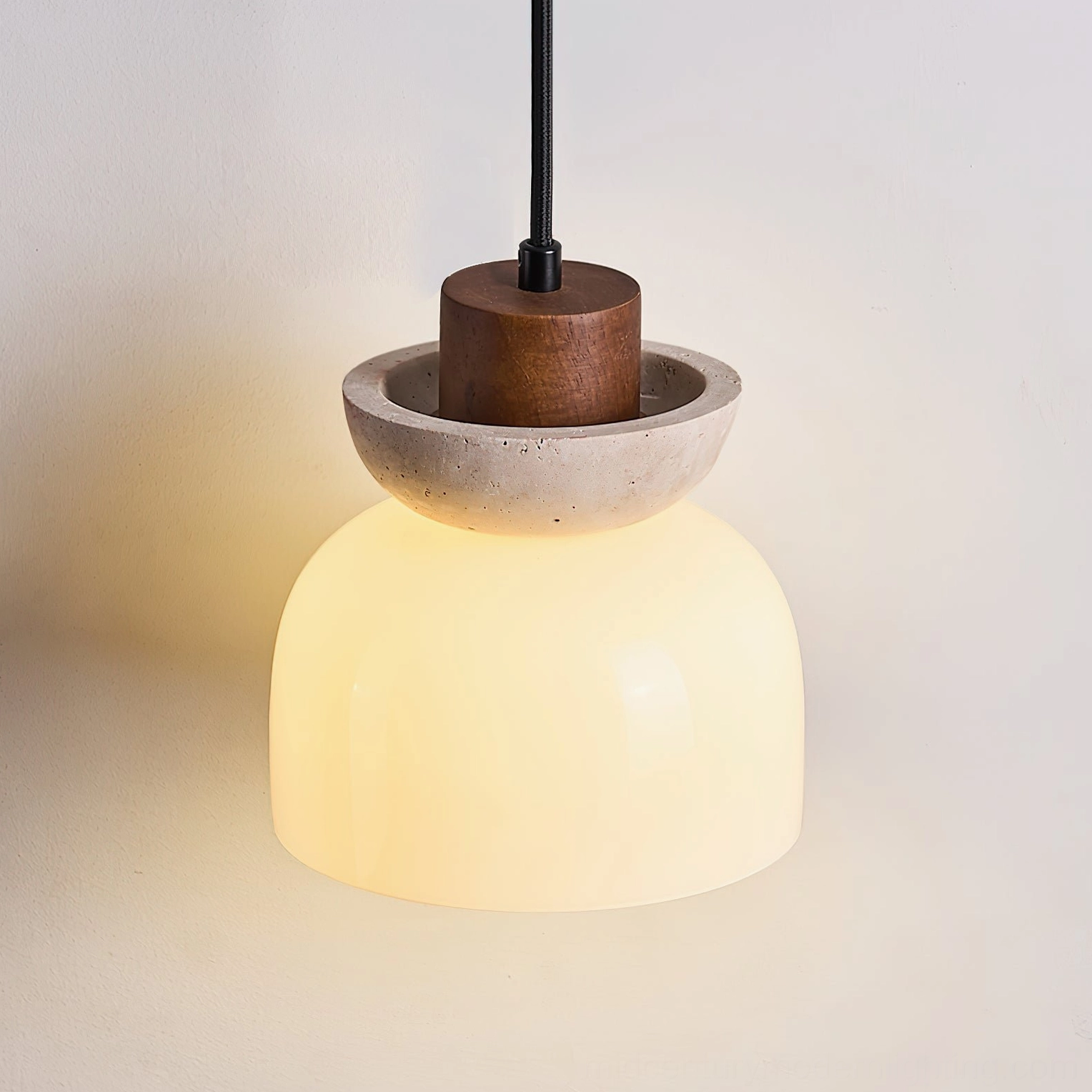 Side view of glowing Palak pendant light warm amber glass diffusion travertine stone accent modern minimalist fixture